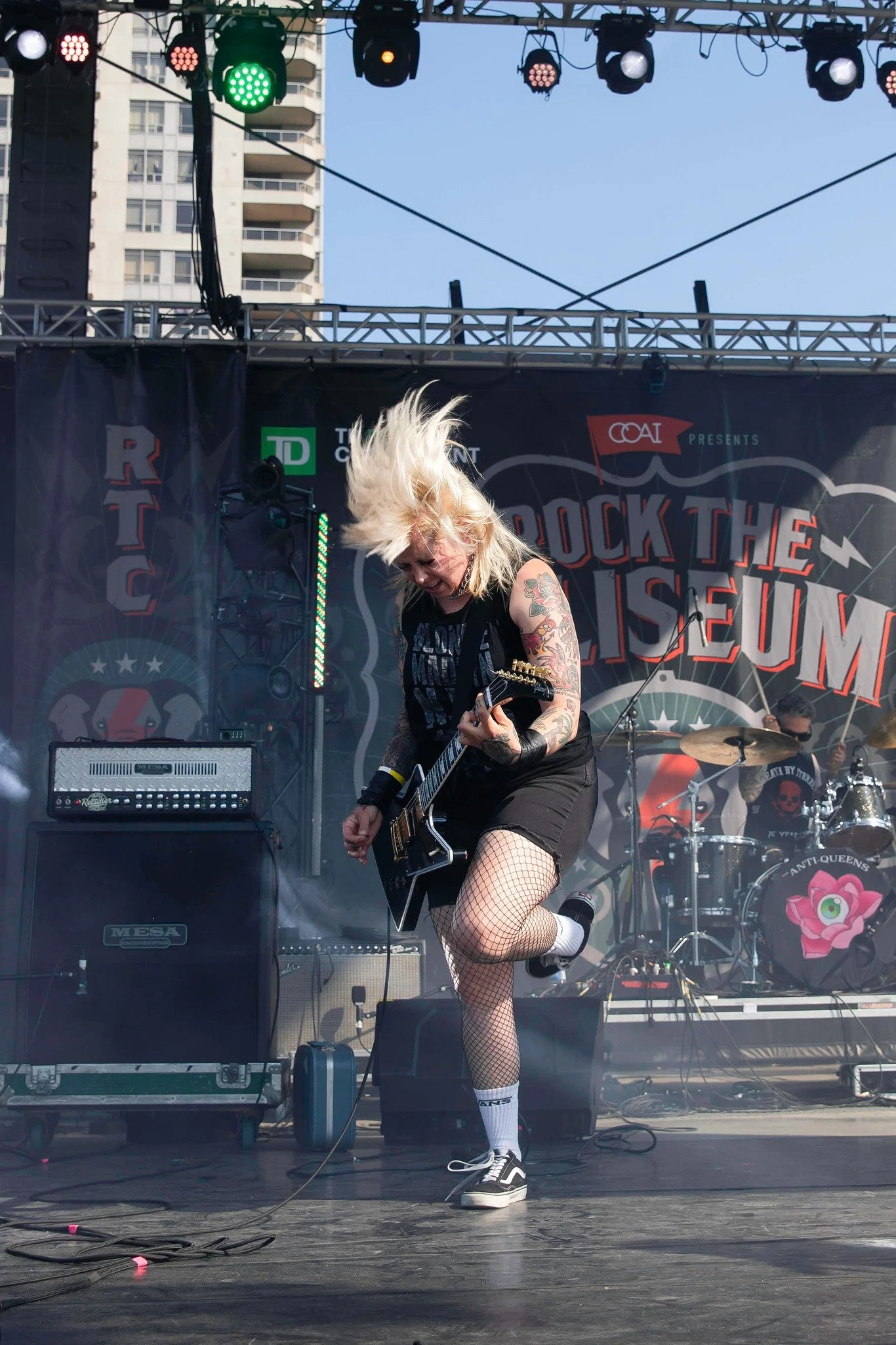 A blonde electric guitar player wearing black playing with passion.