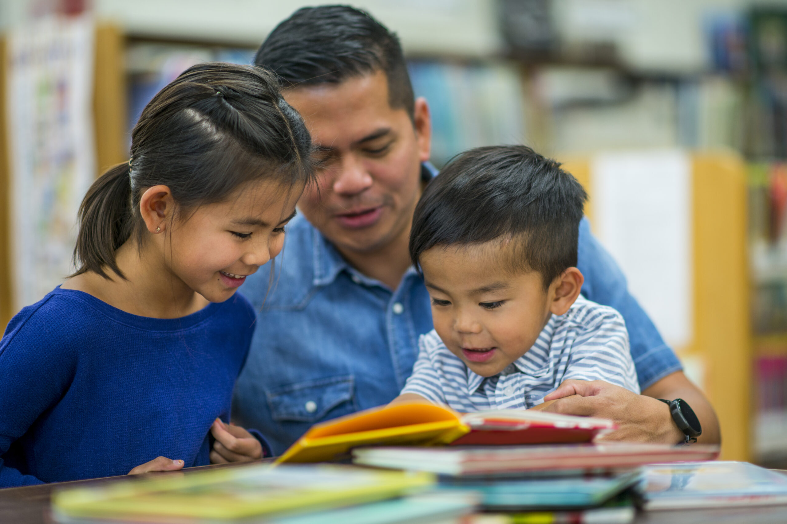 A father is reading book with his children at the library on father's day.